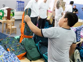 boy holding and looking at green backpack