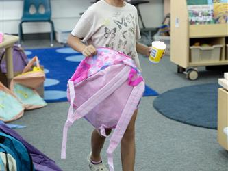 girl with pink backpack and cup in hand walking