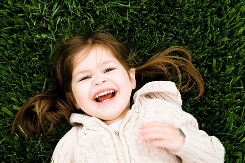 girl laughing and laying in grass